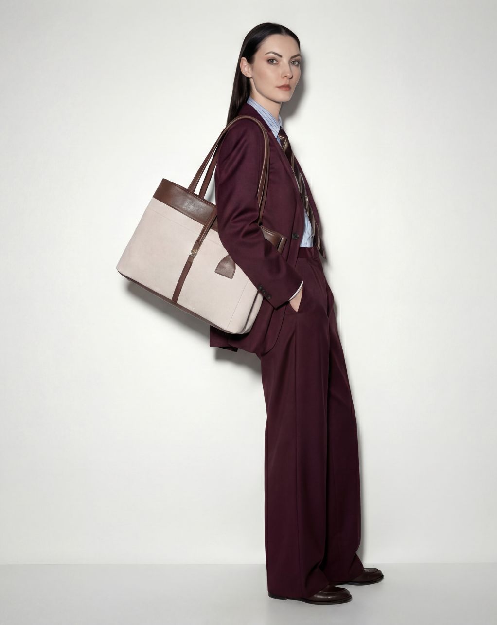 Woman in a burgundy suit holding a beige & brown mindy large tote 