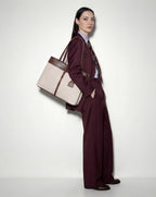 Woman in a burgundy suit holding a beige & brown mindy large tote 
